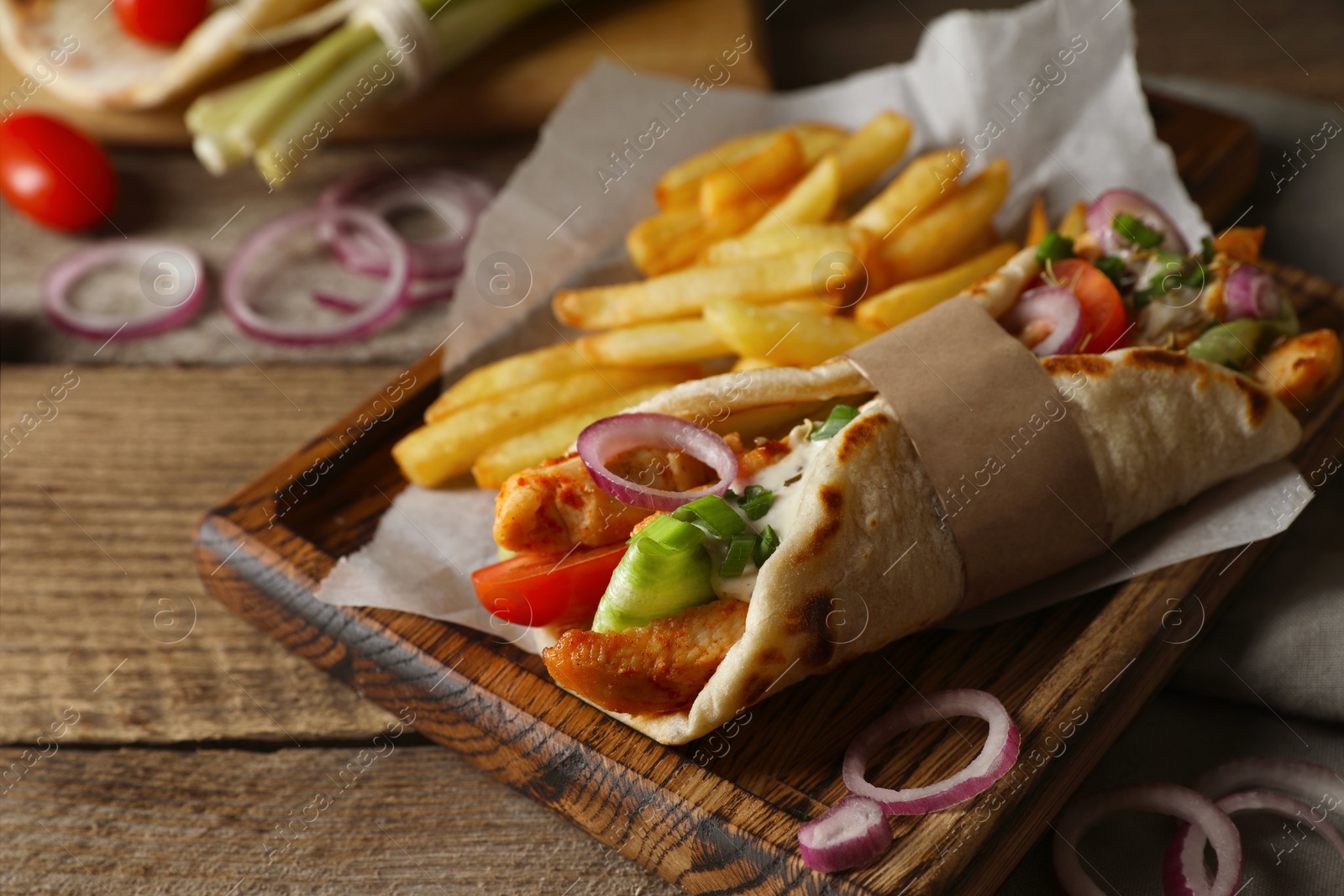 Photo of Delicious pita wrap with meat, vegetables and potato fries on wooden table, closeup