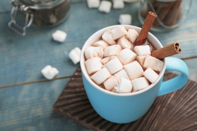 Cup of chocolate milk with marshmallows on wooden table, closeup