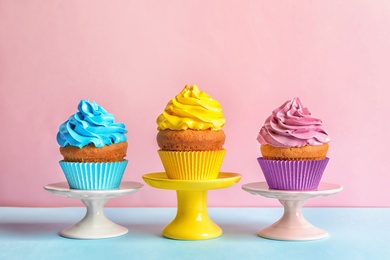 Photo of Delicious birthday cupcakes with cream on color background