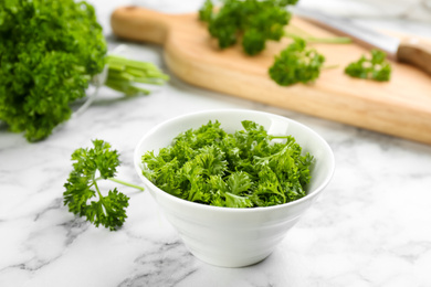 Photo of Cut curly parsley in bowl on white marble table