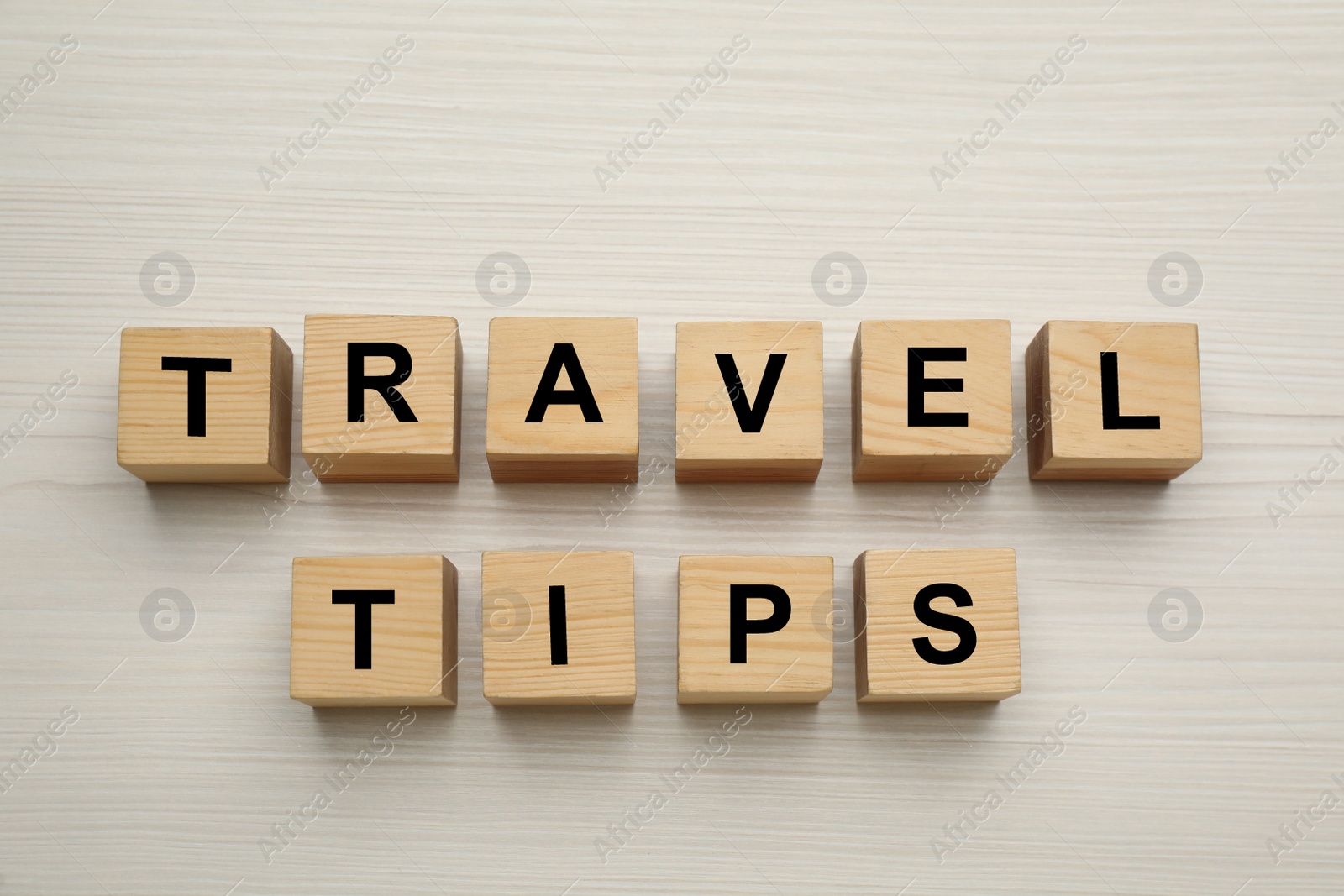 Photo of Phrase Travel Tips made with cubes on white wooden table, flat lay