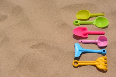Set of colorful beach toys on sand, flat lay. Space for text