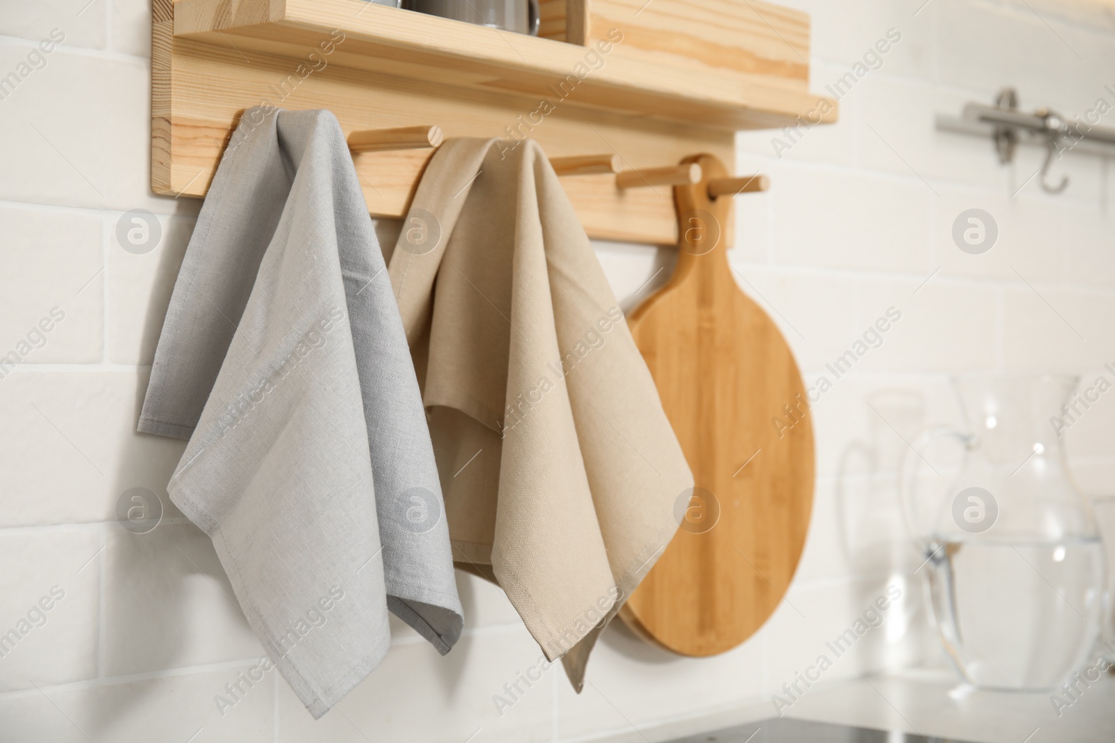 Photo of Different towels and wooden board hanging on rack in kitchen