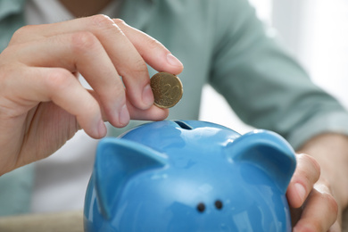 Photo of Man putting coin into piggy bank, closeup