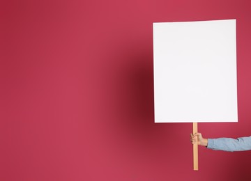 Woman holding blank sign on pink background, closeup. Space for design