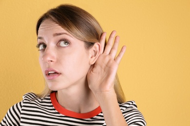 Young woman with hearing problem on color background