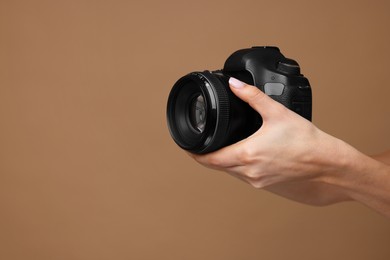 Photo of Photographer with camera on brown background, closeup. Space for text