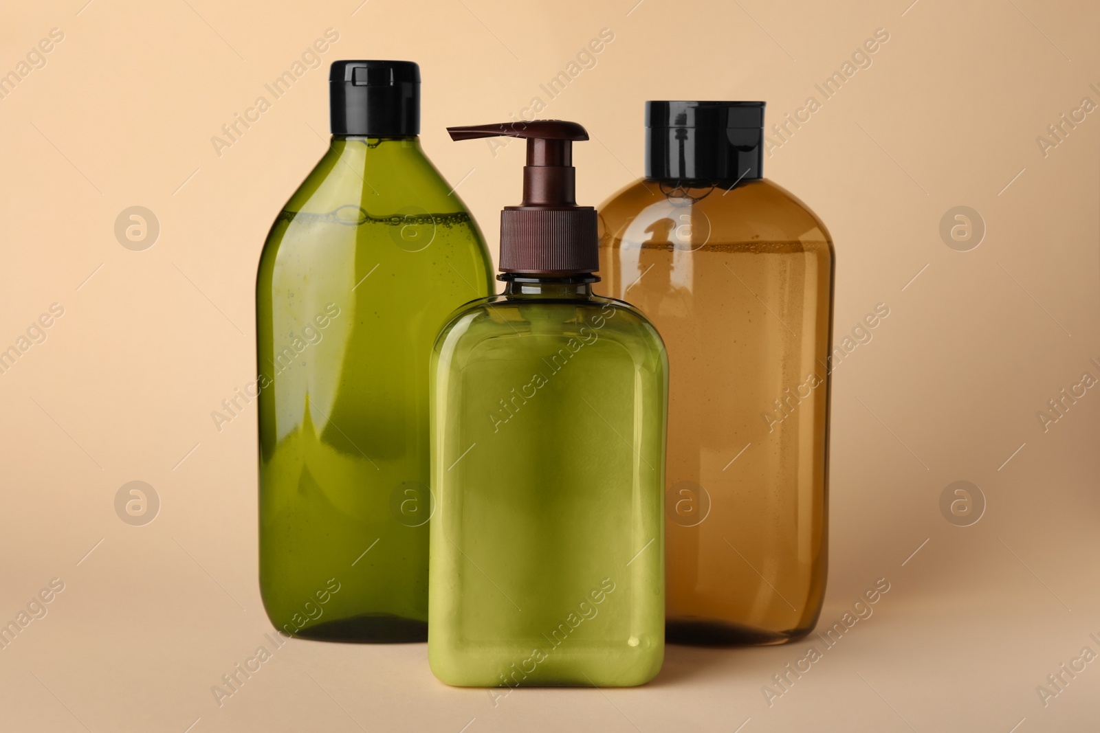 Photo of Different bottles of shampoo on beige background