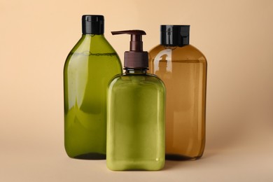 Different bottles of shampoo on beige background