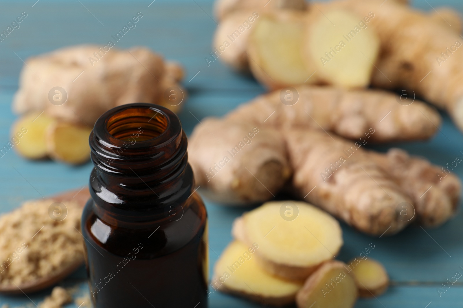 Photo of Glass bottle of ginger essential oil on light blue table, closeup. Space for text