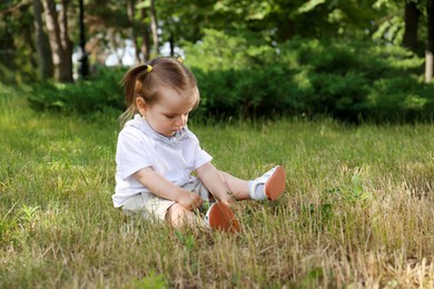 Photo of Cute girl sitting on grass in park, space for text