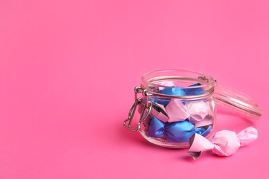 Photo of Candies in colorful wrappers on pink background. Space for text