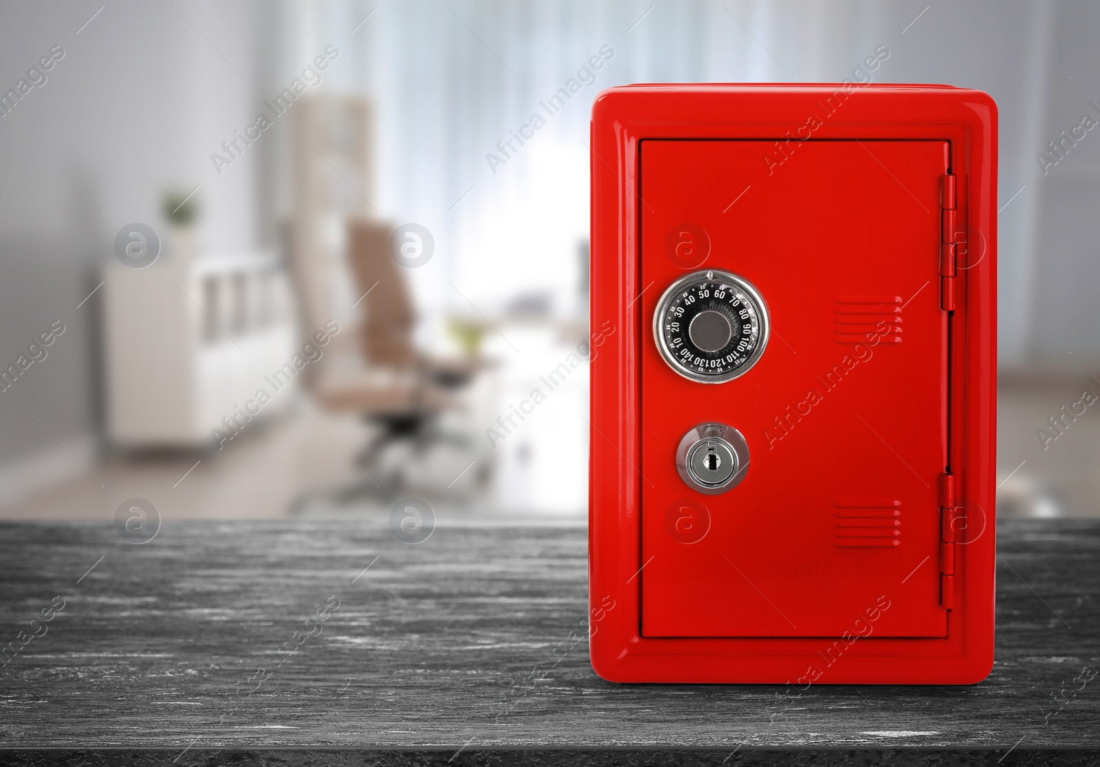 Image of Red closed steel safe with mechanical lock on grey wooden table indoors. Space for text