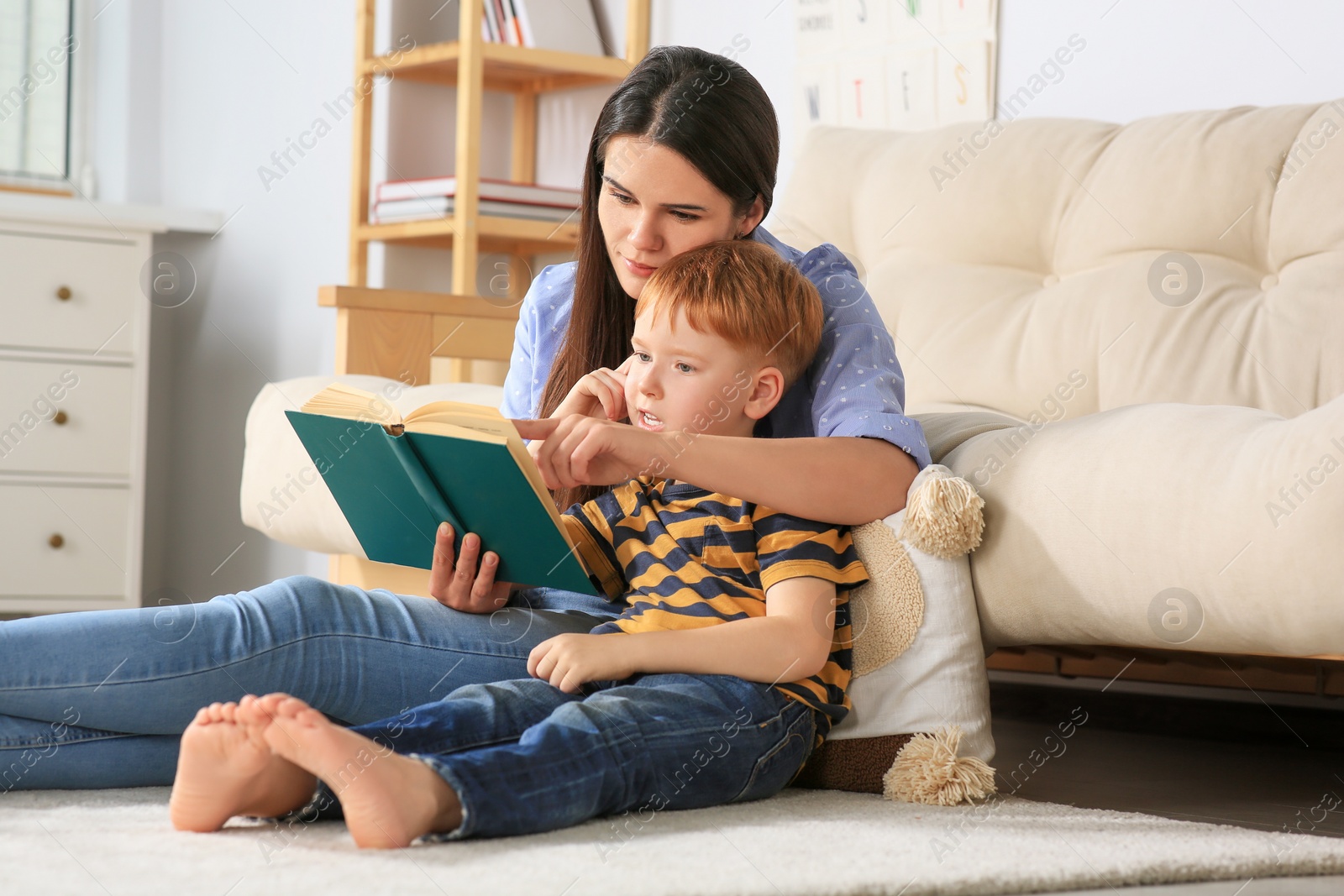 Photo of Mother reading book with her son in living room at home