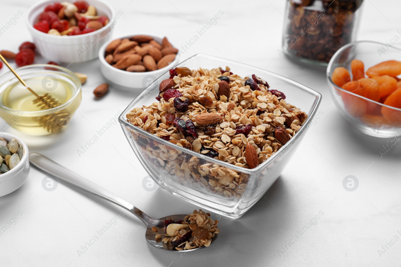 Photo of Tasty granola served with nuts and dry fruits on white marble table