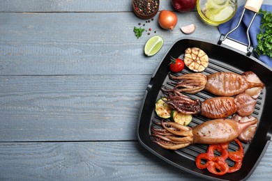 Photo of Tasty grilled squids with vegetables served on grey wooden table, flat lay. Space for text