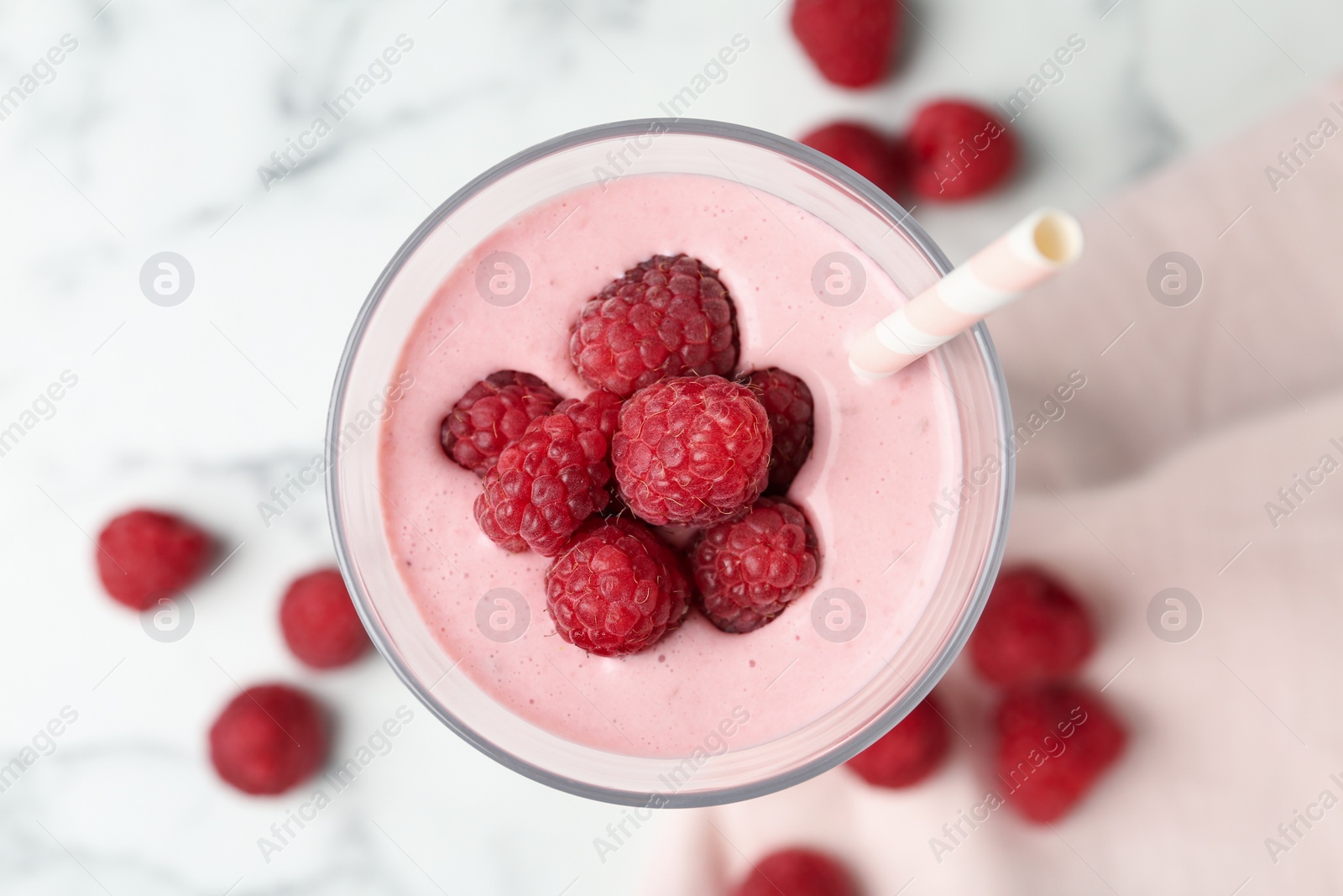 Image of Yummy raspberry smoothie in glass on white marble table, top view