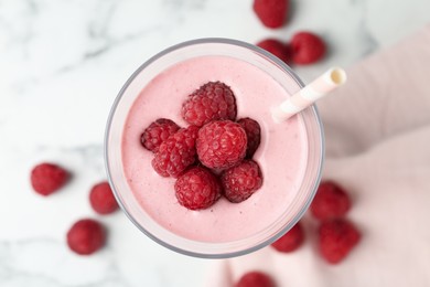 Yummy raspberry smoothie in glass on white marble table, top view