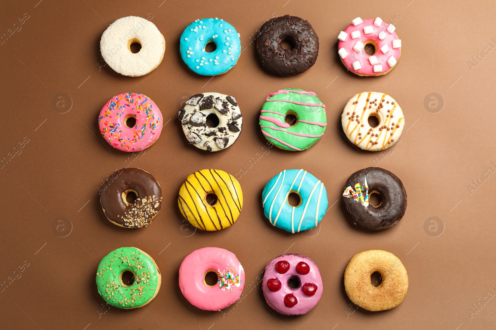 Photo of Sweet tasty glazed donuts on brown background, flat lay