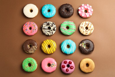 Sweet tasty glazed donuts on brown background, flat lay