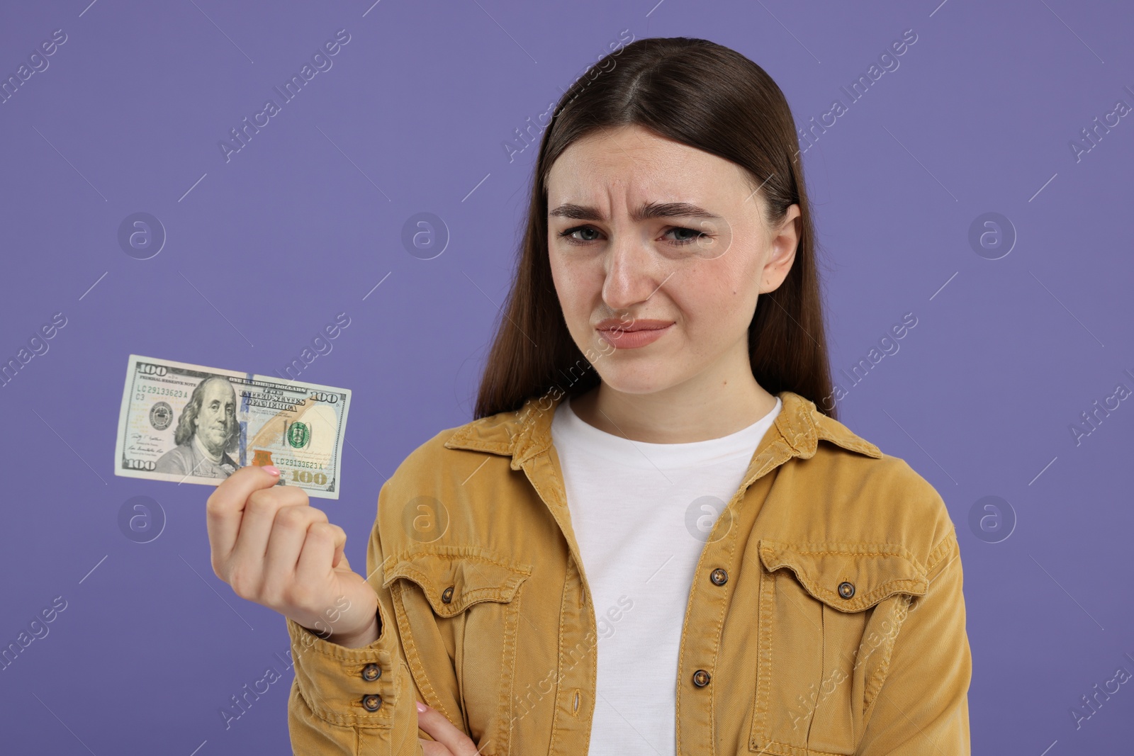 Photo of Sad woman with dollar banknote on purple background