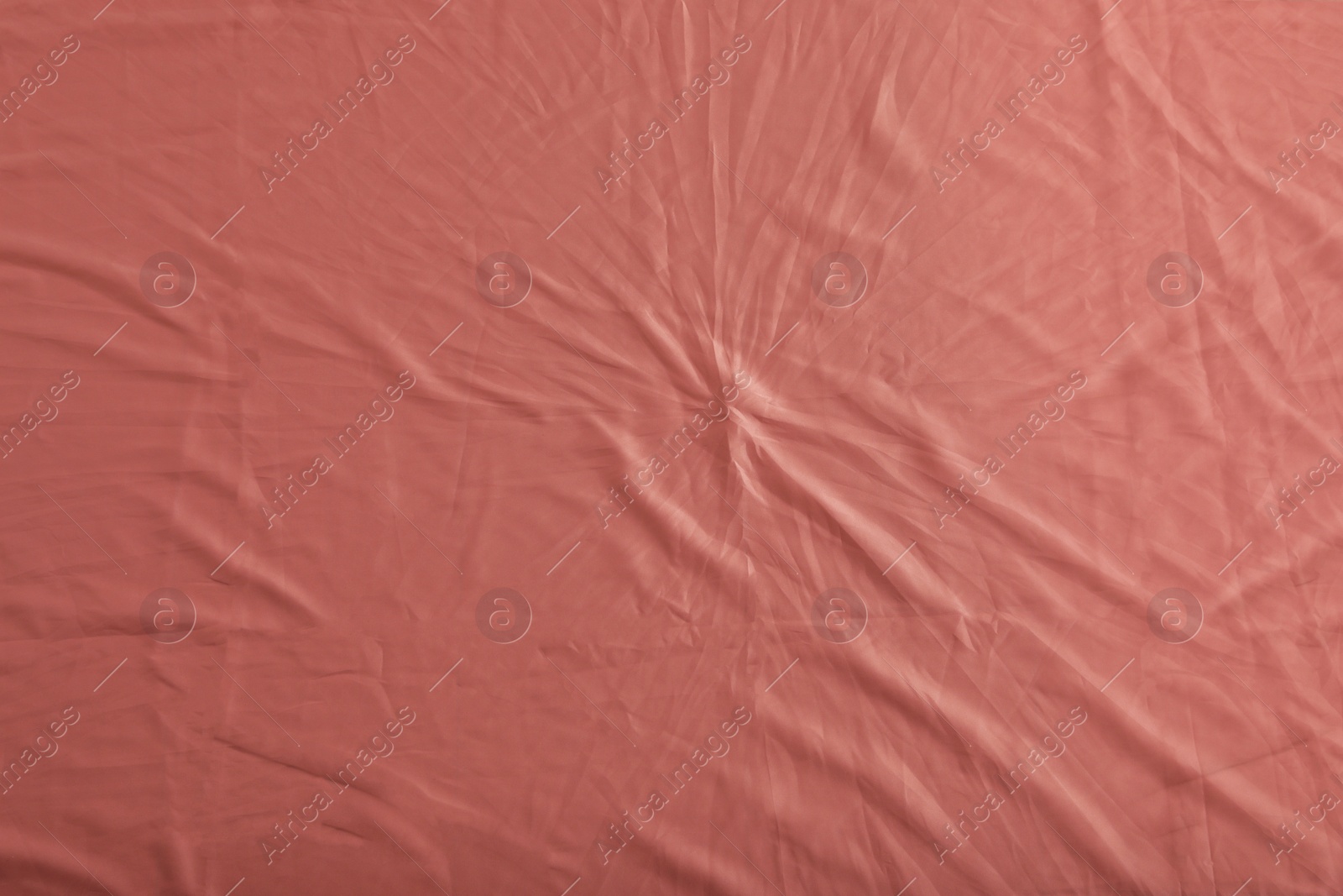 Photo of Crumpled coral fabric as background, top view