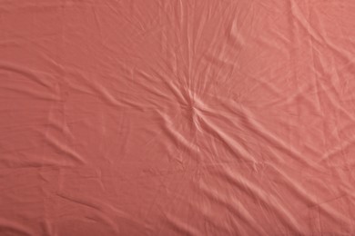 Photo of Crumpled coral fabric as background, top view