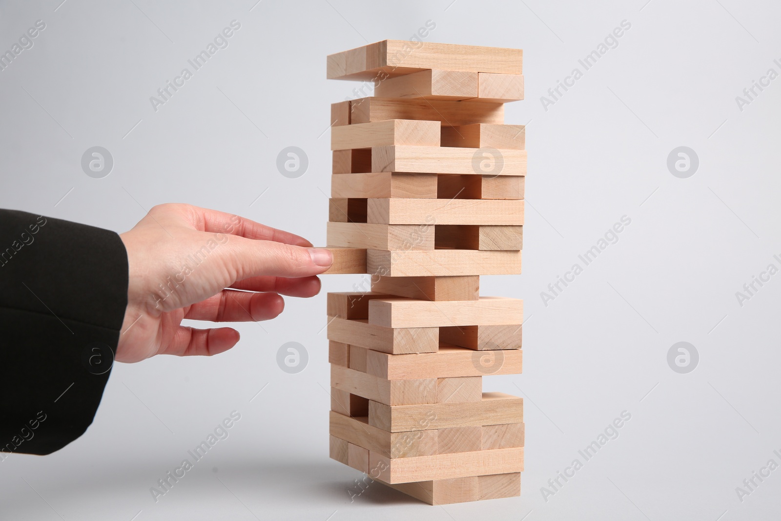 Photo of Woman playing Jenga on light gray background, closeup