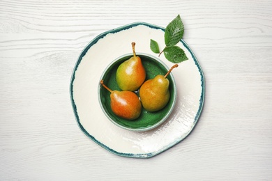 Dishware with pears on wooden background, top view