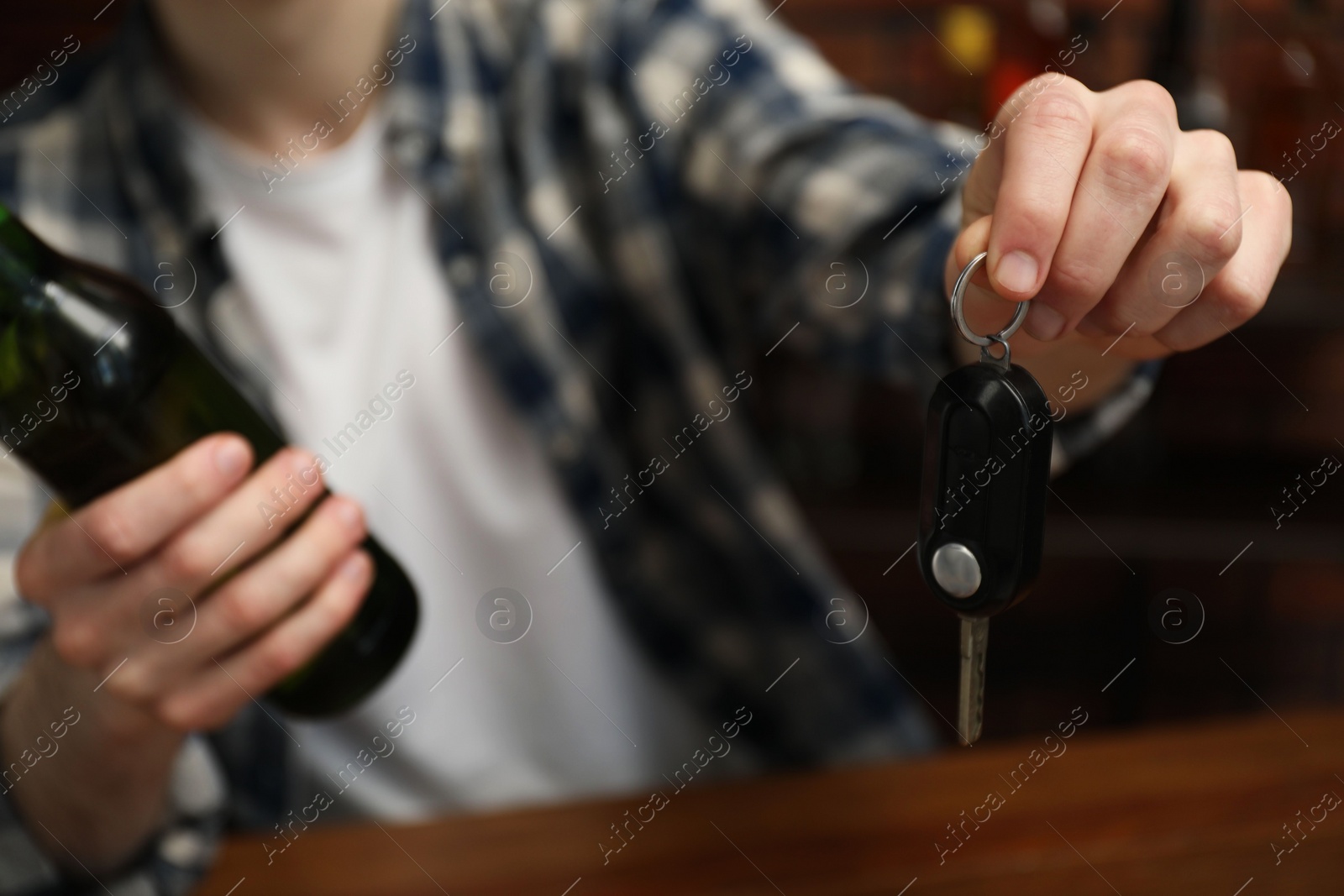 Photo of Man with bottle of beer and car keys in bar, closeup. Don't drink and drive concept