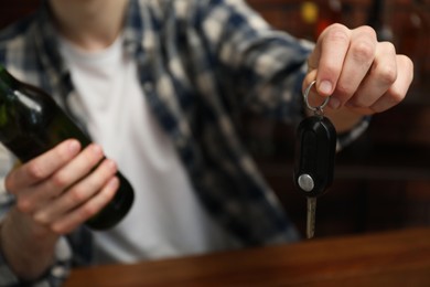 Photo of Man with bottle of beer and car keys in bar, closeup. Don't drink and drive concept