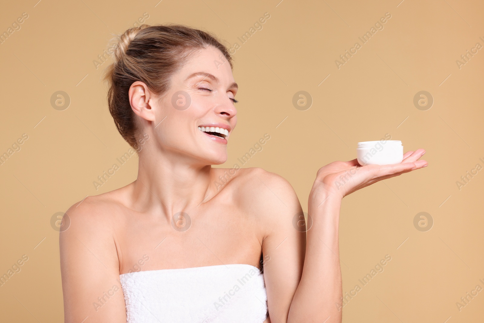Photo of Woman with jar of body cream on beige background