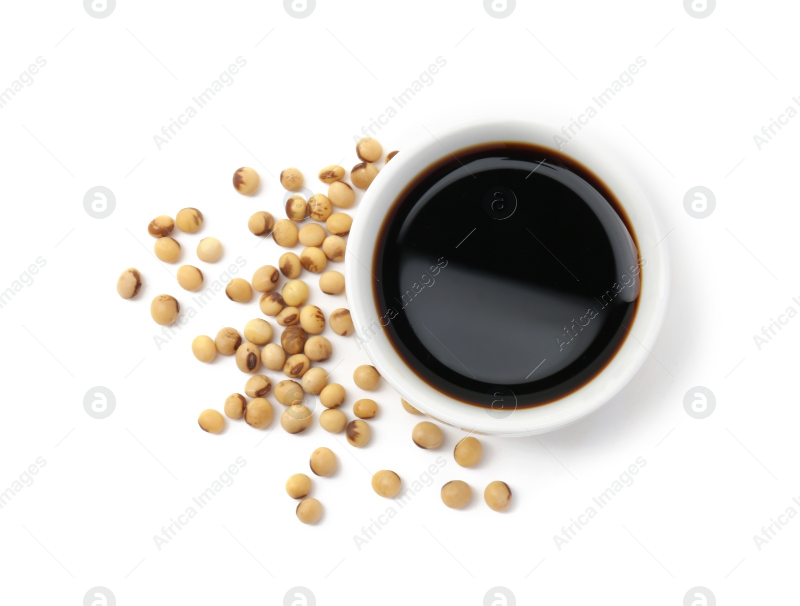 Photo of Tasty soy sauce in bowl and soybeans isolated on white, top view