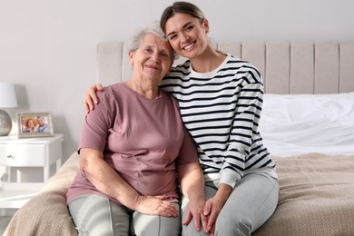 Photo of Young caregiver and senior woman in bedroom. Home care service