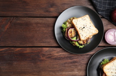 Photo of Delicious eggplant sandwiches on wooden table, flat lay. Space for text
