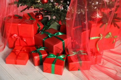 Photo of Beautifully wrapped gift boxes under Christmas tree indoors