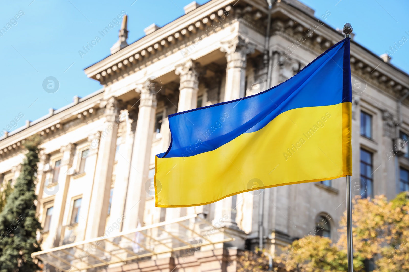 Photo of National flag of Ukraine fluttering near building on sunny day