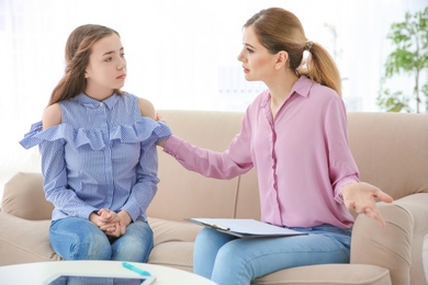 Photo of Female psychologist working with teenager girl in office