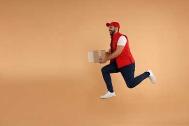 Photo of Happy courier running to deliver parcel on light brown background, space for text