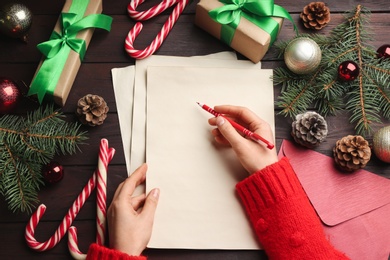 Top view of woman writing letter to Santa at wooden table, closeup