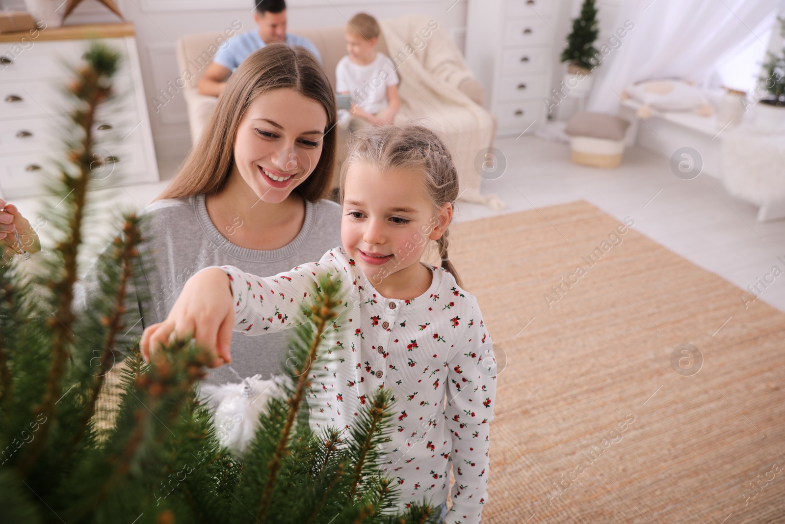 Photo of Mother with daughter decorating Christmas tree together at home