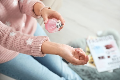 Photo of Young woman using perfume indoors, closeup. Space for text