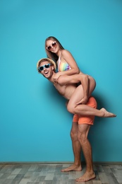 Photo of Happy young couple in beachwear against color wall