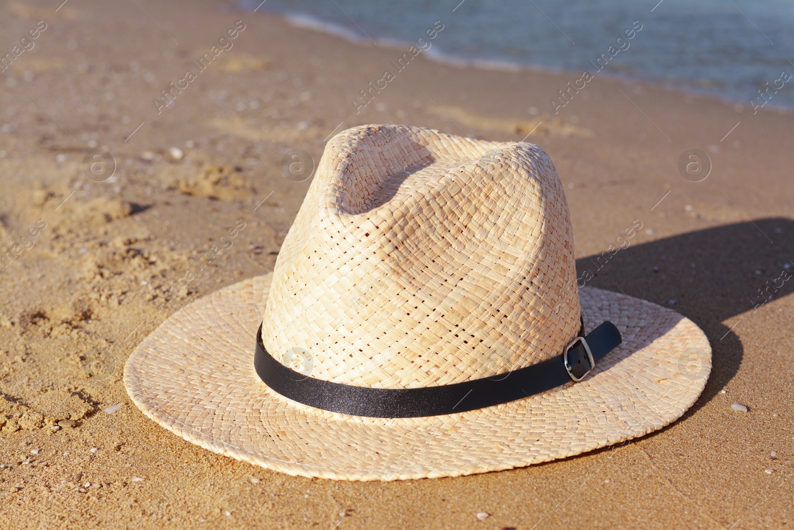 Photo of Stylish straw hat on sandy beach near sea