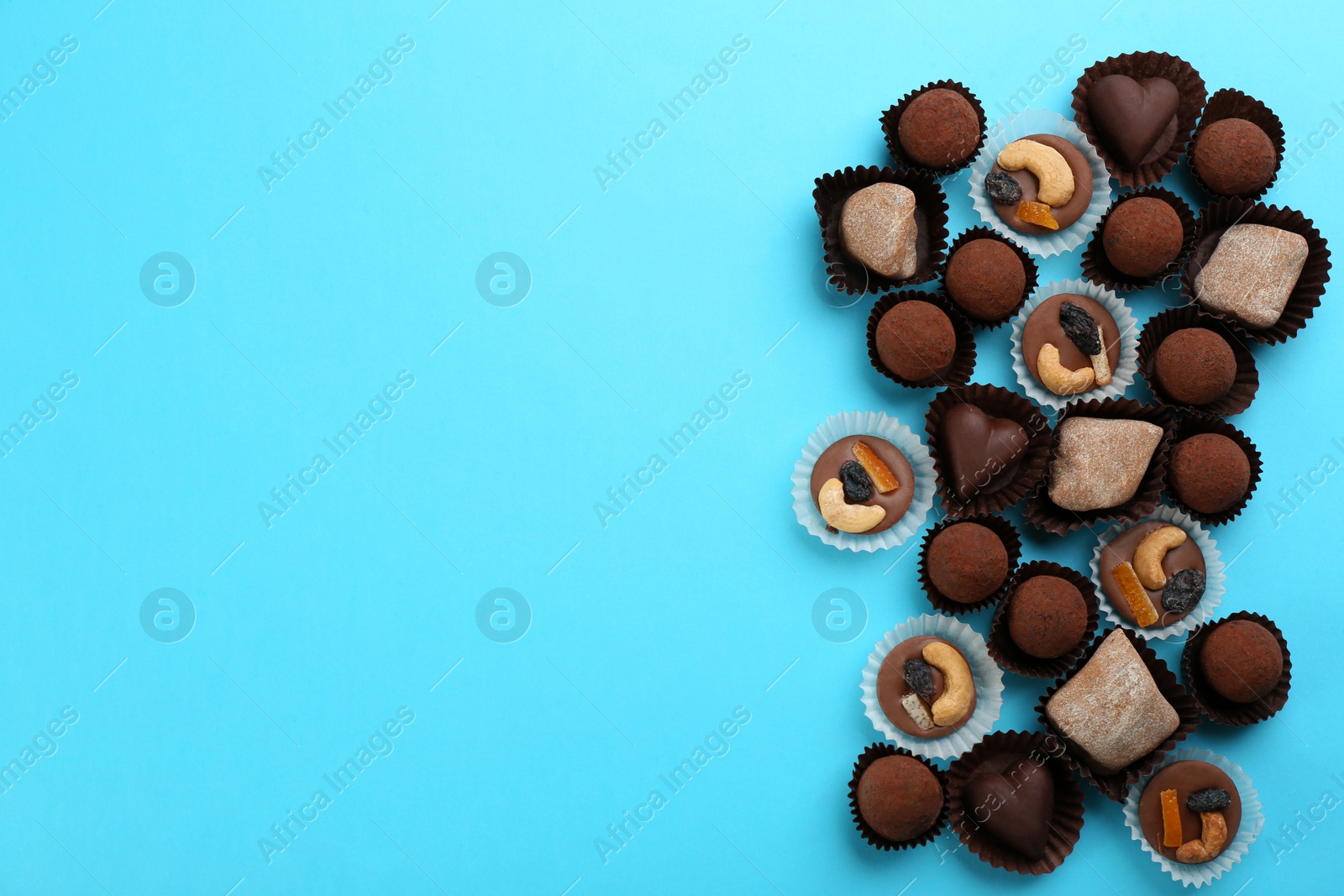 Photo of Different delicious chocolate candies on light blue background, flat lay. Space for text