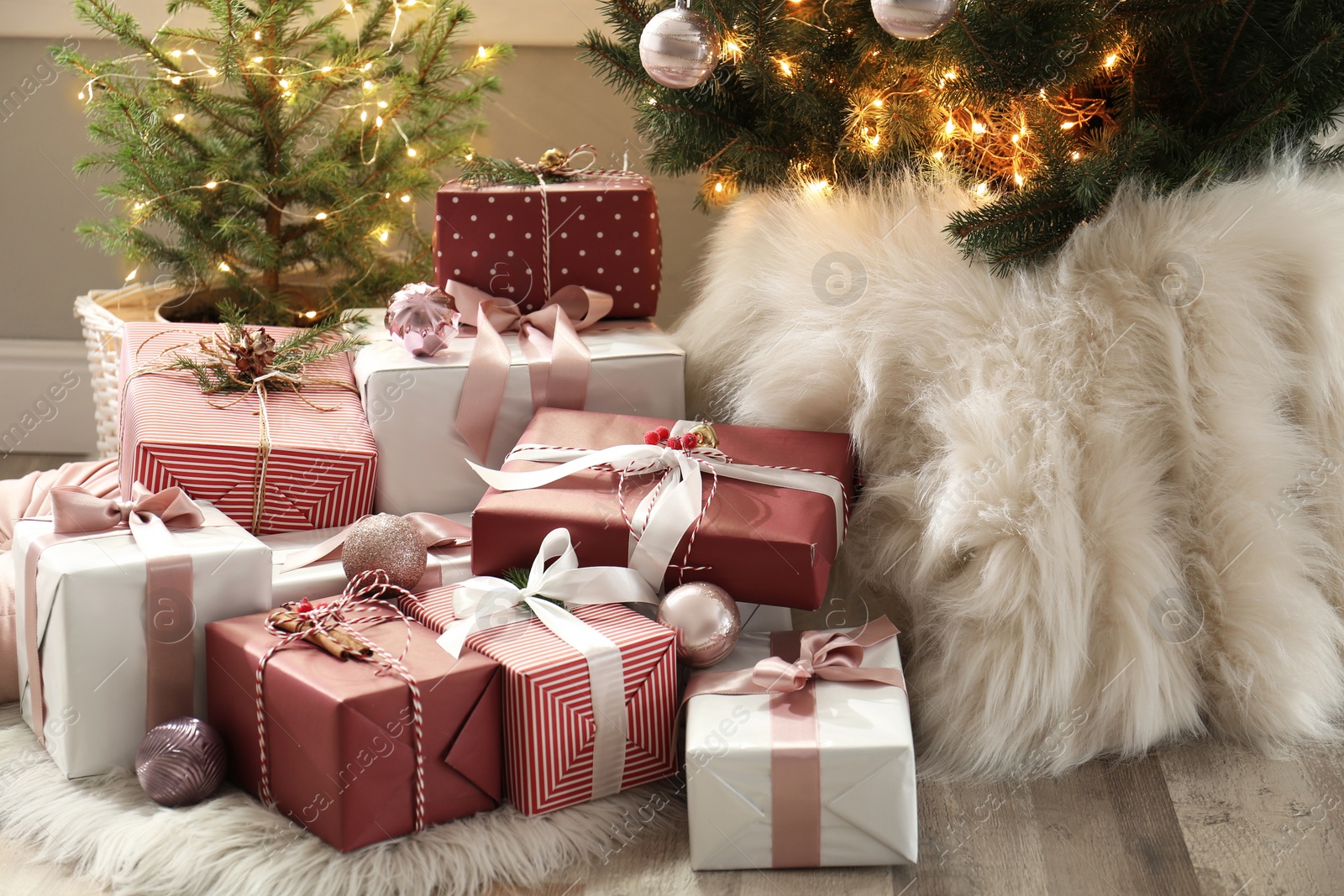 Photo of Gift boxes under small and big Christmas trees indoors