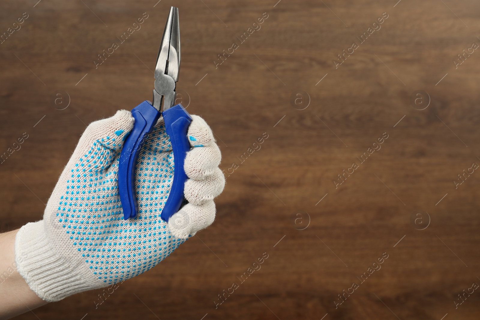 Photo of Man with needle nose pliers on wooden background, closeup. Space for text