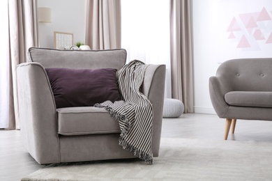 Photo of Comfortable armchair with soft cushion in modern living room interior. Space for text