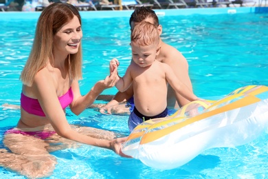 Photo of Happy family with little child resting in swimming pool outdoors