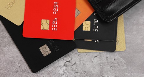 Photo of Pile of different credit cards on grey table, closeup